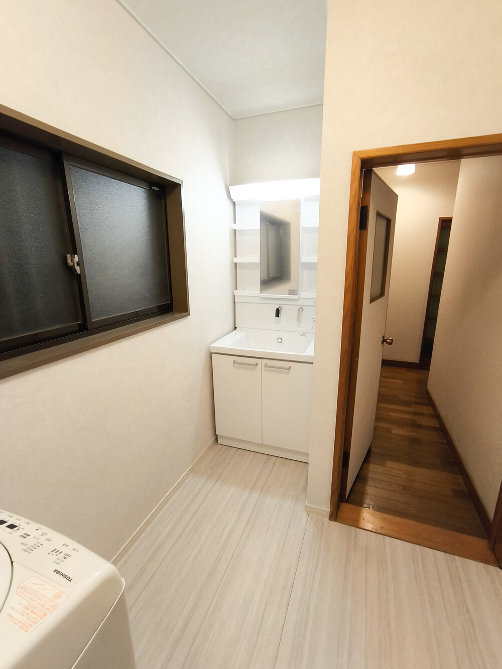 白を基調とした明るい洗面所。清潔感があり、空間が広く感じられます 。