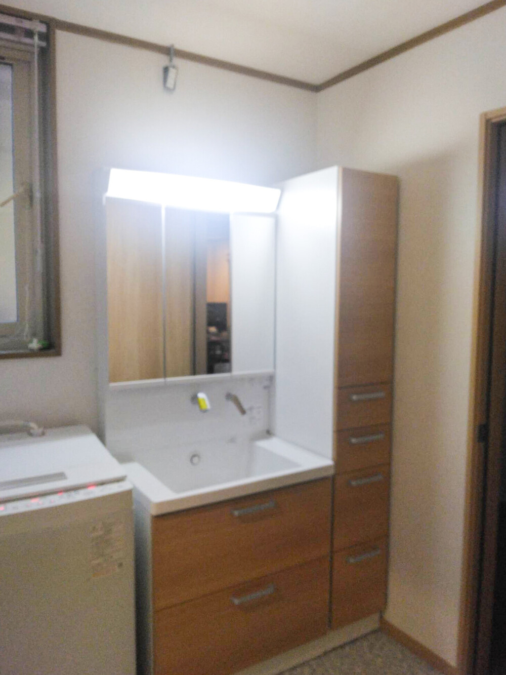 トールキャビネットの設置で収納力が劇的に向上。木目調のデザインで統一し、清潔感と温かさを両立しました。