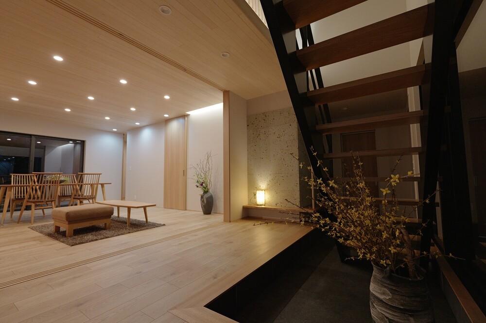 既存建物で南面に面したリビングだった空間をタイルテラスを持つ玄関ホールへ改修しました。日射取得型トリプルガラス樹脂サッシ、吹き抜け空間とし２階からも日射を取り入れ、130mmネオマゼウス基礎断熱のタイル仕上げの土間床とし南面の日射取得を蓄熱できる空間へ。また東京から帰省した際に子供が気兼ねなく２階ゲストルームに上がれる様に階段も配置し、動線にも配慮しました。