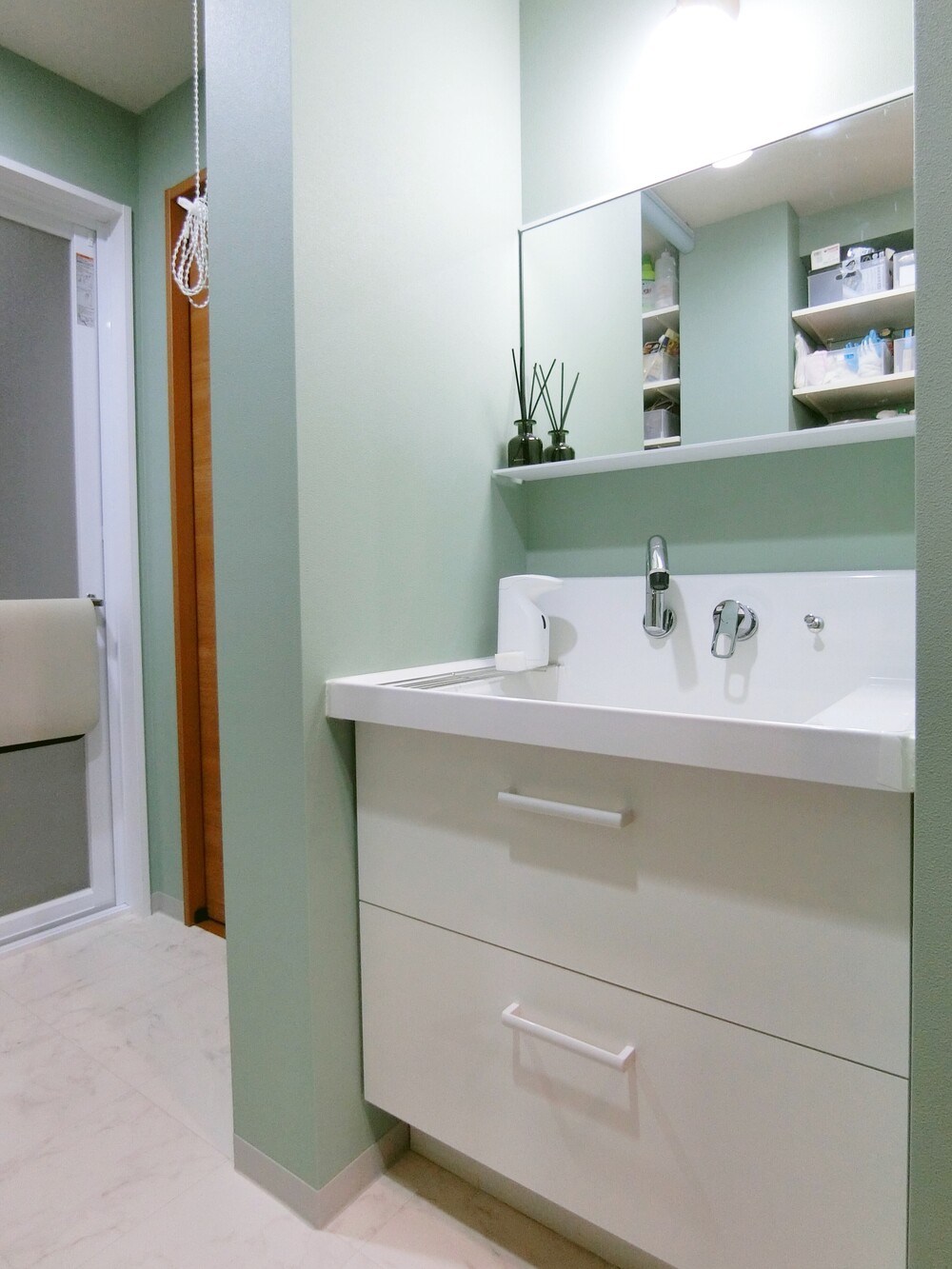 洗面台の背面は、可動棚で自由度の高い収納に。無印良品の引き出しなど、使いたい収納グッズのサイズに合わせて棚板を設計しています。棚柱を三分割にすることで、掃除機などの長尺物も収まるようにしました。