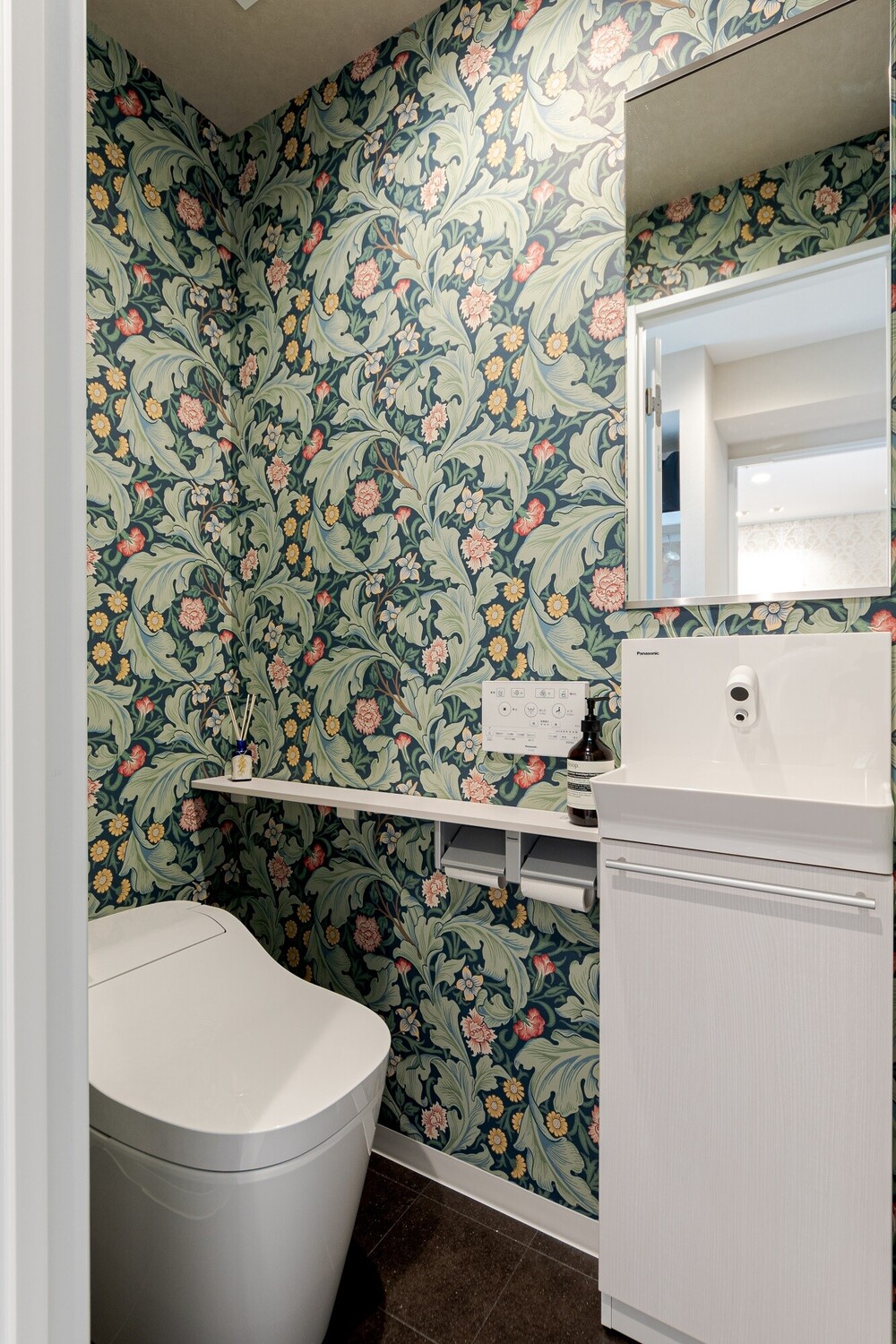 選定したパナソニック製の「アラウーノ」は、流すたびに泡で洗浄してくれ、水アカ汚れが付きにくい優れもの。また手洗い器の自動水栓は、水の飛び散りを防ぐバックガート付きです。ボタニカルなクロスが印象的な、明るく華やかなトイレへと生まれ変わりました。